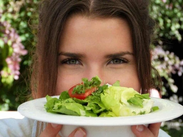 de vrouw houdt een bordje salade vast