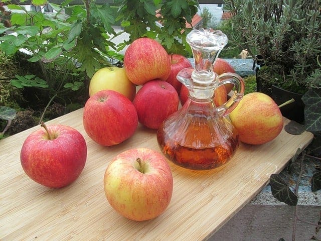 Verse appels en een fles appelciderazijn op de tafel