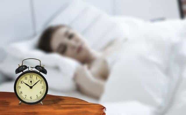  een vrouw slaapt met een wekker naast haar bed