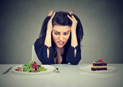  een vrouw zit aan een tafel met een bord cake en een bord salade