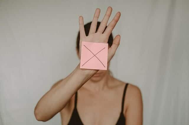 een verdrietige vrouw houdt een kartonnen doos met een x voor haar