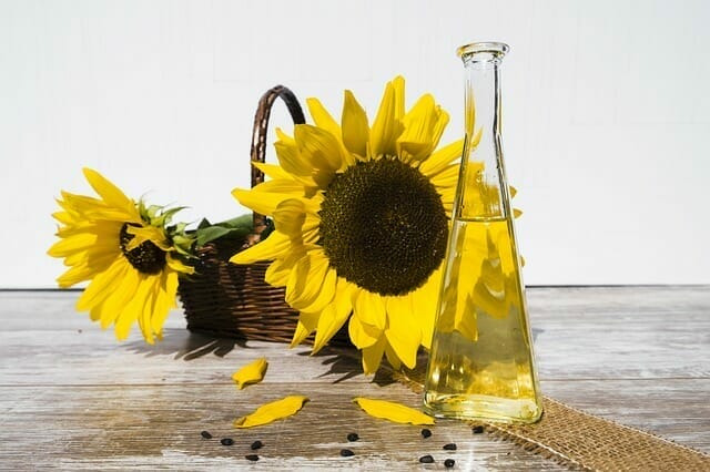  Een flacon olie naast zonnebloemen