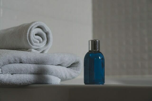  blauwe fles met shampoo, handdoeken ernaast