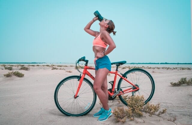  vrouw drinkt water uit een fles na een fietstocht