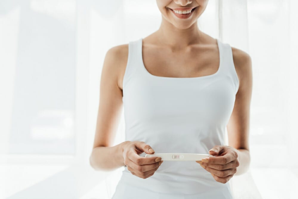  een tevreden vrouw houdt een positieve zwangerschapstest vast